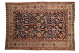 Antique Qashqai carpet with intricate, colorful pinwheel and animal motifs on a dark navy blue field.
