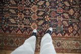 Perspective view of intricate pinwheel florals and vines on an antique navy Qashqai carpet.