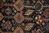 Artistic detail of pinwheel florals and multi-colored vines on a hand-knotted antique Qashqai rug.