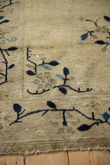 Close-up of antique Peking rug's beige field with meandering blue vine and blossom detail, short fringe.