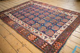 Kurdish rug showing repeating copper boteh, ivory banding, and chocolate brown geometric border.