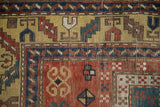 Antique Kazak rug corner detail with yellow ground serrated leaf border and geometric red field.