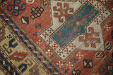 Antique Kazak rug detail showing brick red field, geometric crab motifs, and yellow ground border.