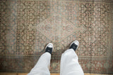 Antique distressed Senneh rug with muted floral patterns, abrashes, and visible wear underfoot.