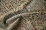 Decorative distress and muted floral patterns on a folded antique Senneh rug.