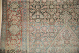 Detailed floral patterns and worn texture of antique Senneh rug, in muted red and silver.