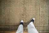 Distressed antique Malayer rug with feet, showcasing faded Herati design and worn texture.
