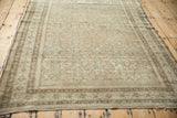 Worn edge of distressed Malayer rug, showing faded Herati design in oxidized silver and pale brown.