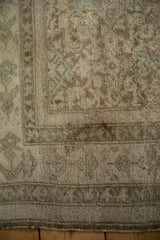 Distressed antique Malayer rug detail: faded Herati pattern, dusty blue, and tattered edge.