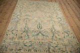 Distressed cream Persian Yezd rug, unidirectional floral field, forest green vines, faded blue accents.