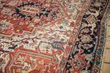 Traditional Persian Heriz carpet: green corner spandrel, polychromatic selvage, navy border.