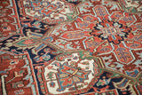 Vintage Heriz rug section with geometric blossoms and floral arabesques in brick red and navy.