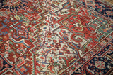 Close-up of vintage Heriz carpet with geometric floral motifs and green corner spandrel.