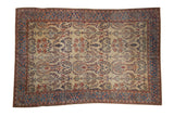 Antique Farahan Sarouk carpet with a sand-colored field of floral sprays and botehs inside a contrasting dark blue border.