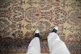 A view of the reciprocating floral sprays and botehs on a sand-hued antique Farahan Sarouk carpet.