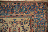 Intricate floral corner of a Farahan Sarouk rug with a sky blue border and sand-colored field.