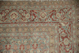 Distressed vintage Tabriz rug corner with dusty blue and madder red Samovar vine border.