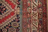 Detailed border design with vibrant gem tones on an antique Malayer carpet.