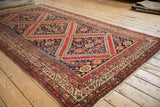 Close-up of the antique Malayer carpet's vivid red, navy, and saffron pomegranate medallion.