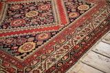 Antique Malayer carpet, vivid tomato red borders and navy field with pomegranate motifs.
