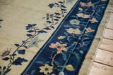 Navy blue floral border and original tattered side cord of an antique hand knotted Peking carpet.