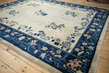 Corner view of an antique Peking carpet showing the interconnecting floral vine border in navy blue.