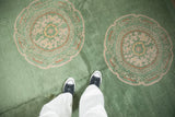 Dusty mint green field of an antique Nichols Art Deco carpet, featuring beige and pale gold roundel medallions.