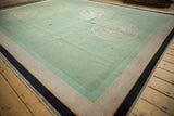 Corner of an Art Deco carpet; dusty mint field, pale gold medallion, striped borders, and worn edge.