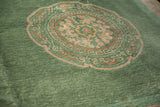 Textured pile of a jade green, pale gold Art Deco medallion on dusty mint.