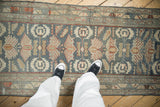 A top-down perspective showing the finned palmettes and distressed texture of the vintage Malayer runner.