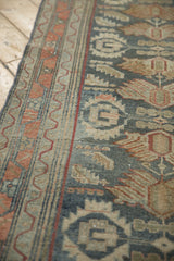Detail of the serrated leaf border and low, worn pile on a vintage Malayer rug runner.