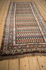 Angled view of a vintage Kurdish Hamadan runner with staggered rows of colorful botehs.
