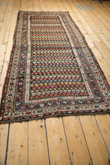 Angled perspective of a vintage Kurdish Hamadan runner with rows of colorful boteh motifs.