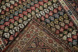 A folded corner of a vintage Kurdish rug showing the boteh-patterned pile and hand-knotted foundation.
