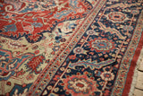 Wide navy floral border next to the cherry red field of a vintage Heriz carpet.