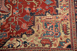 Corner detail of a vintage Heriz rug with serrated leaf motifs in gem tones of red, blue, and saffron.
