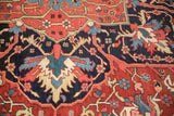 Detailed serrated leaves and palmettes in red and navy on a hand-knotted vintage Heriz rug.