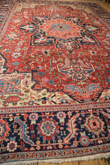 Low angle view along a vintage Heriz carpet, showing its navy border and expansive red field.