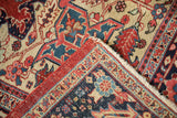 Corner detail of a vintage Heriz carpet showing the intact red selvage and dense, hand-knotted pile.