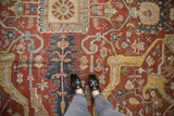 A personal view showing the scale and low pile of an antique Heriz carpet's bold geometric motifs.