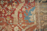 Detail of the hand-knotted pile showing large floral designs in cherry red, dusty blue, and saffron.