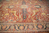 Angled view of an antique Heriz carpet's oversized arabesques and traditional floral motifs.