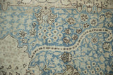 Detail of geometric blossoms and serrated leaves in dusty blue and silver on a low pile.