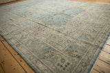 The distressed corner of a vintage Tabriz rug, with low-pile texture and a slate blue floral border.