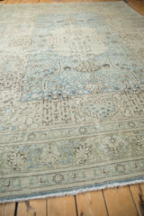 Low angle view across the distressed vintage Tabriz carpet, showing the texture of its low pile and sprawling floral field.