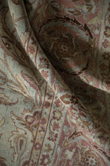 Folded detail of distressed Yezd carpet showing even wear, powder blue, and blush vine motifs.