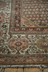 Distressed Kurdish Hamadan rug corner with richly patterned border and softened burgundy tones.