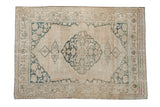 Distressed Antique Doroksh rug with ivory field, dusty teal medallion, and vine borders, 4' x 5'8
