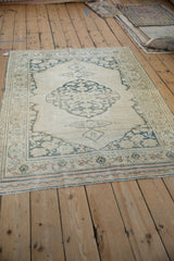 Distressed lower corner of antique Doroksh rug, with ivory field and dusty teal vine border.