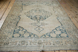 Distressed ivory and dusty teal scrolling vine main border with meandering outer line.